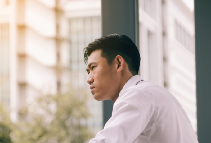 Young man looking anxiously out of window