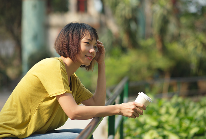 Smiling woman drinking a coffee in a park