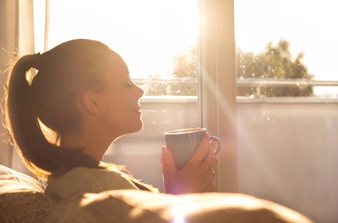 Woman sitting at home drinking a cup of tea relaxing