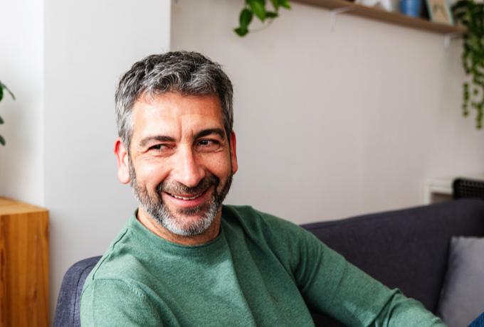 Male sitting on couch at home smiling happily