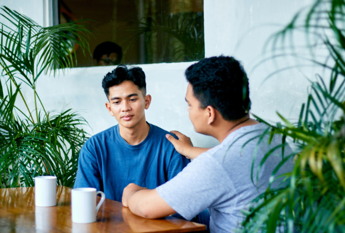 Friends sitting at a table supporting one another talking privately