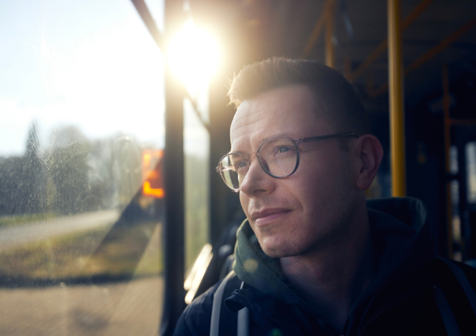 Close up of man on the bus looking out the window pensively.
