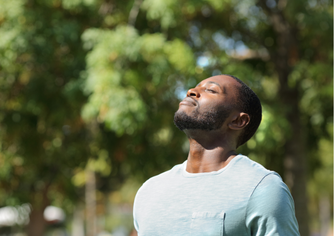 Male standing outside in nature doing deep breathing, practicing mindfulness