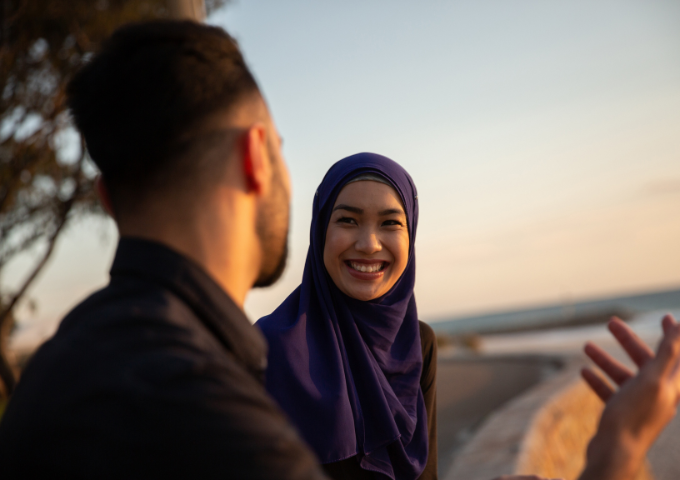 Two friends smiling happily talking outside